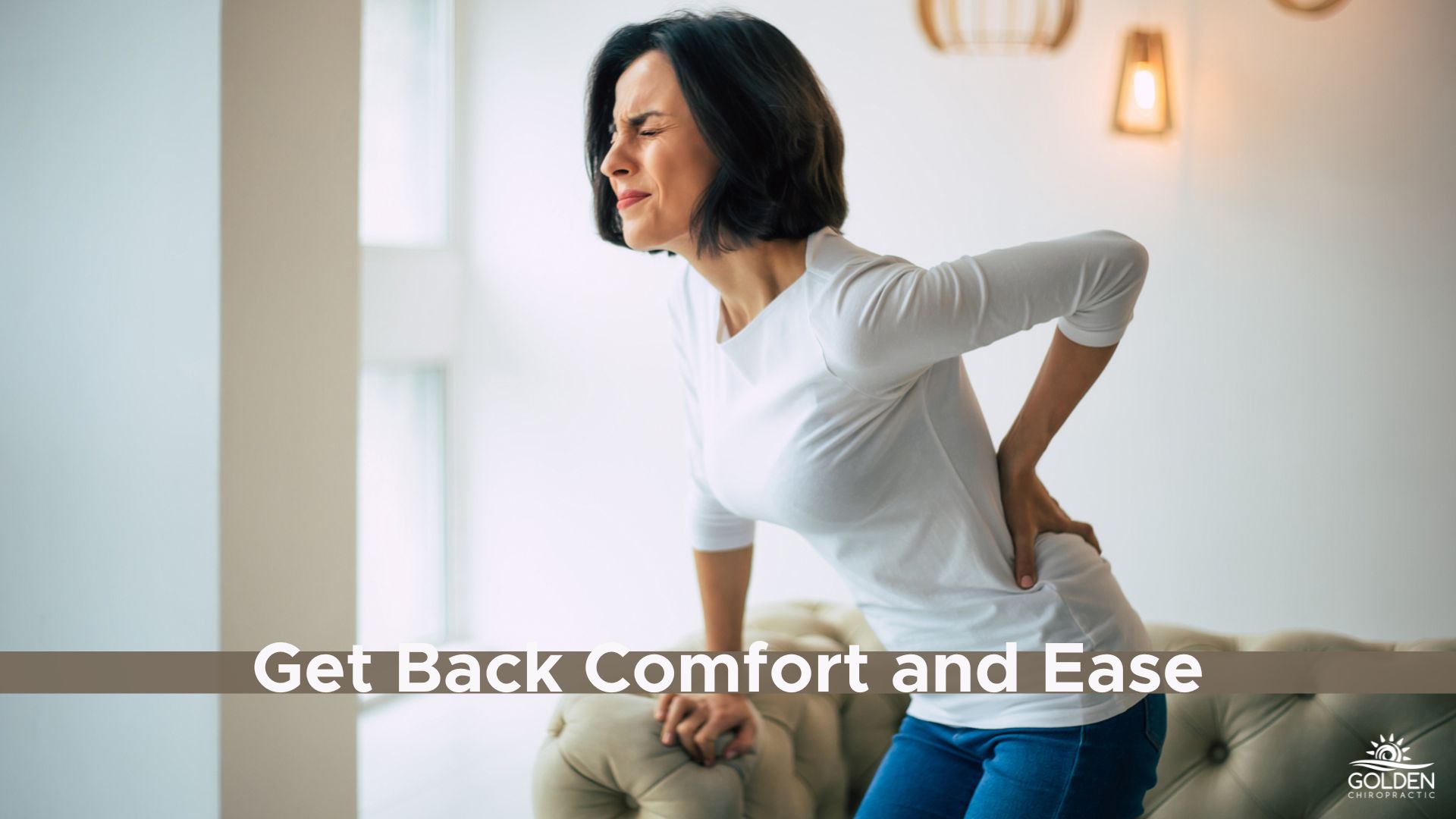 Middle age woman clutching her lower back and grimacing in pain